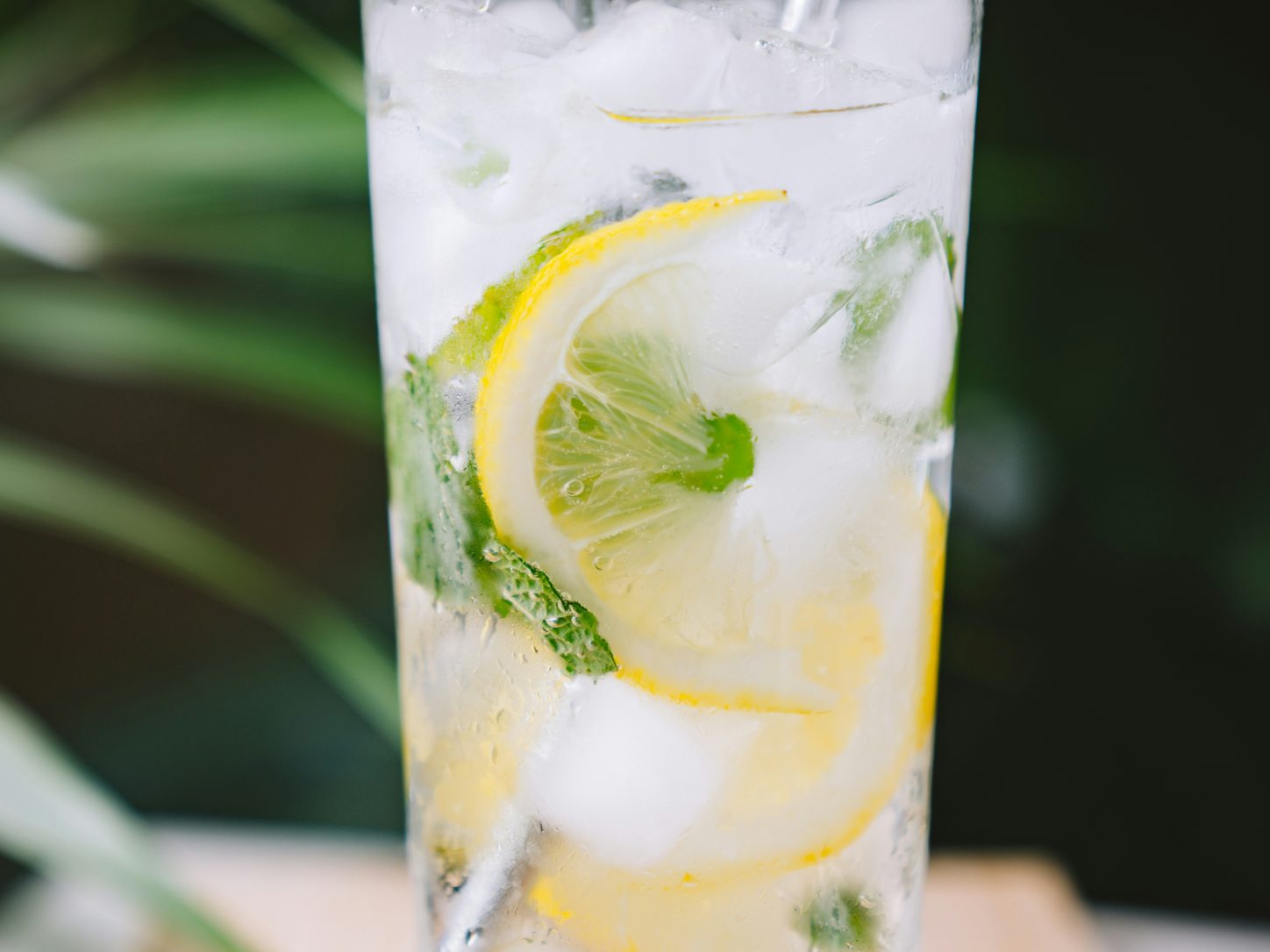 Glas Wasser mit Zitrone und Minze, umgeben von Eiswürfeln